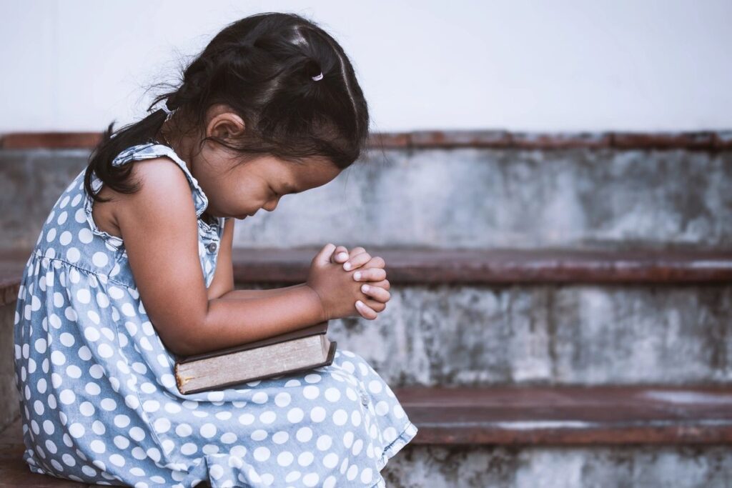 child holding book in prayer
